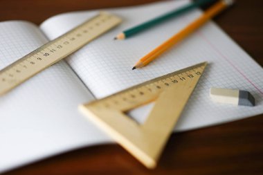 Kırtasiye, masada ofis malzemeleri, açık defter, cetveller, kalemler ve bir silgi