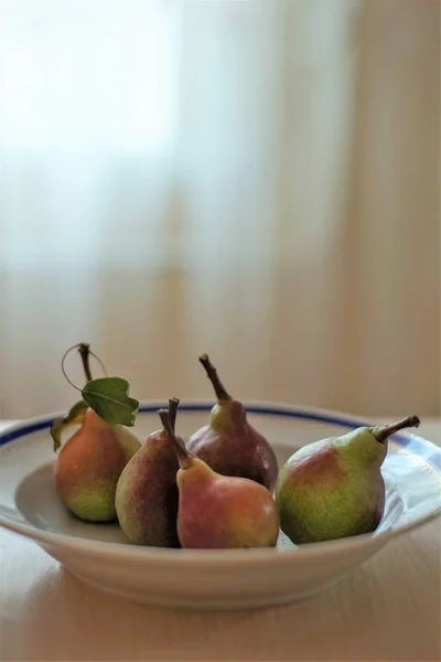 Peras maduras en un plato profundo sobre la mesa . — Foto de Stock