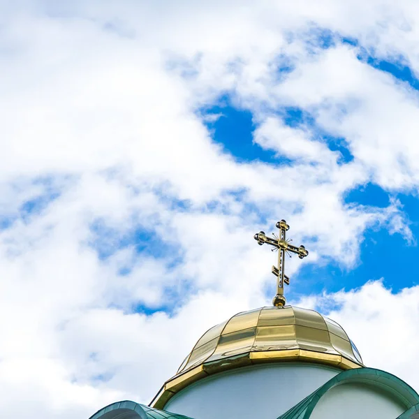 Koepel met een gouden kruis orthodoxe kerk. Blauwe hemel met witte wolken. — Stockfoto