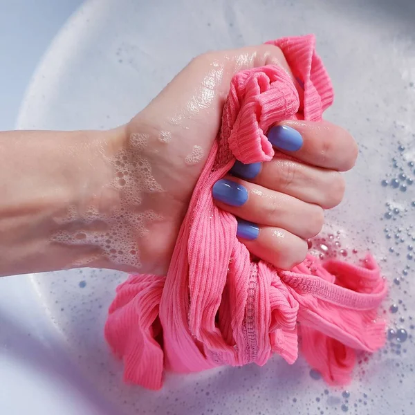 파란색 손톱을 가진 여성의 손은 분지에 분홍색 티셔츠를 씻어 — 스톡 사진