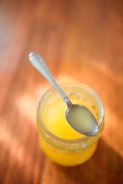 Güneşli ahşap bir masada bal ile Kaşık ve cam kavanoz