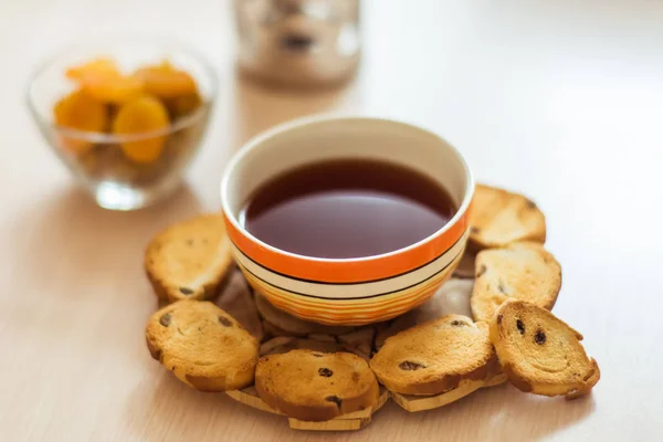 Черный чай в оранжевой чаше и хлебные крошки на столе — стоковое фото