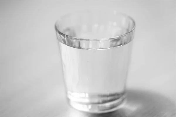 Glass full of water on the table, selective art focus, black and white — Stock Photo, Image