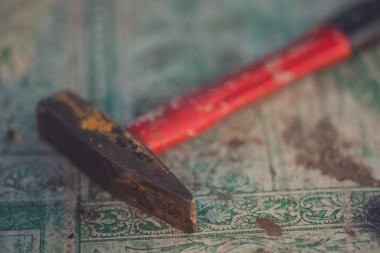 Kırmızı saplı kullanılmış çekiç eski bir kirli masa örtüsü ile bir masa üzerinde yatıyor.