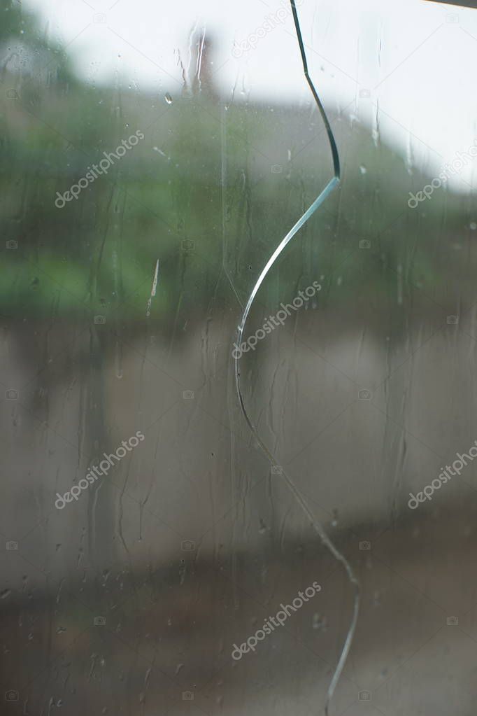 Crack in the glass, it is raining outside the window, sadness an