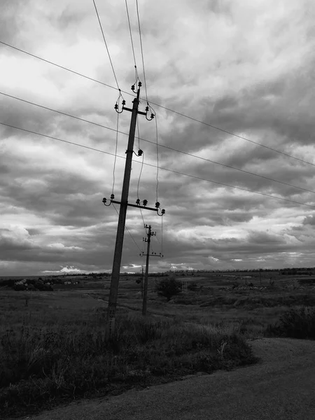 Lantlig gata med gamla elektriska stolpar och väg nära fält, BW foto — Stockfoto