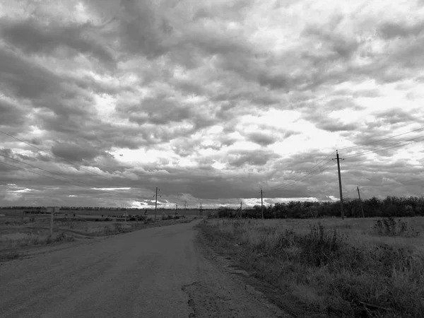 Vieille route rurale près du champ et ciel nuageux — Photo