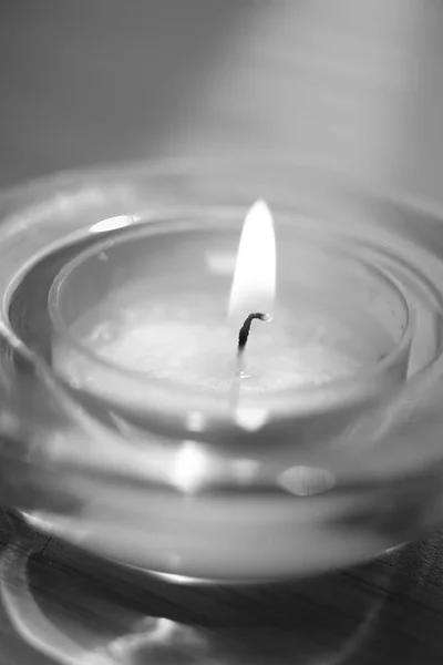 Low candle burns in a round glass candlestick, macro, bw — Stock Photo, Image