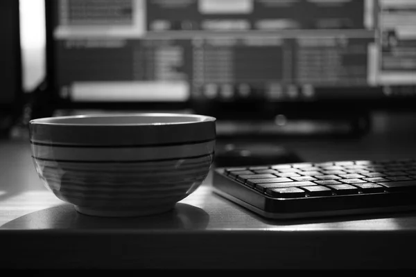 freelancer workspace, tea cup, keyboard and monitor, work environment, black and white photo.