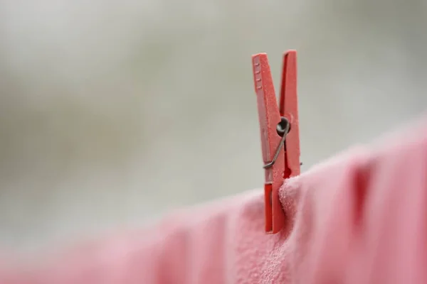 Pinza de ropa roja sostiene la ropa en una cuerda, imagen macro . — Foto de Stock