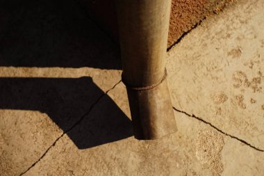 Downpipe at the corner of the building, cracks in the blind area of the house, sunlight and shadow from the drain pipe clipart