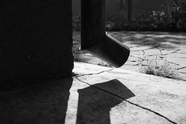 Drenaż na rogu budynku, jasne światło słoneczne i cień z rury spustowej na kamiennej podłodze, BW Photo — Zdjęcie stockowe