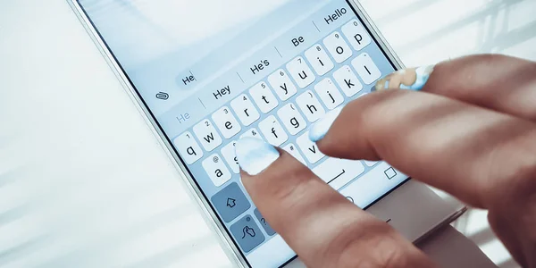 Kobieta ręka z niebieskimi paznokciami pisze na białym telefonie wiadomość — Zdjęcie stockowe
