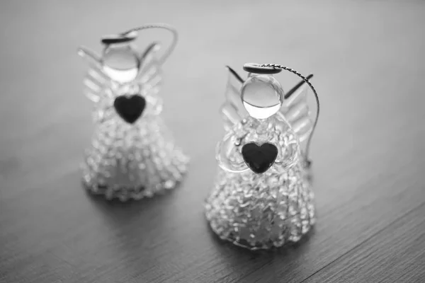 Two small statues of angels with hearts on the table, black and white photo. — Stock Photo, Image