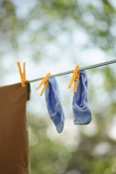 Синие носки высушиваются на веревке с прищепками в саду . — стоковое фото
