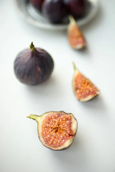 Um figo inteiro e o outro em fatias jazem numa mesa branca. . — Fotografia de Stock