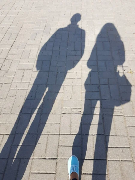 Les ombres d'un homme et d'une femme marchant le long du trottoir . — Photo