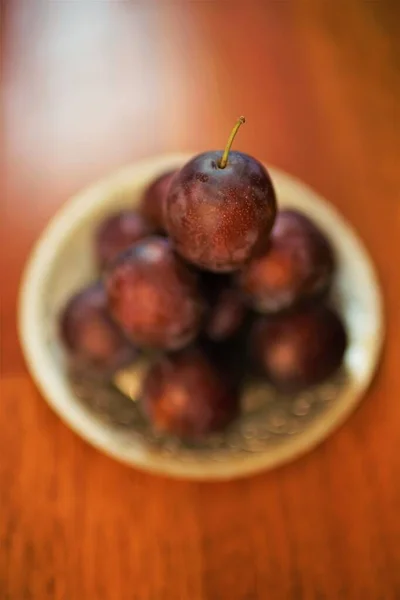 Ciruelas púrpuras maduras en un plato de plata. Frutas frescas en la mesa de madera. Vista superior — Foto de Stock