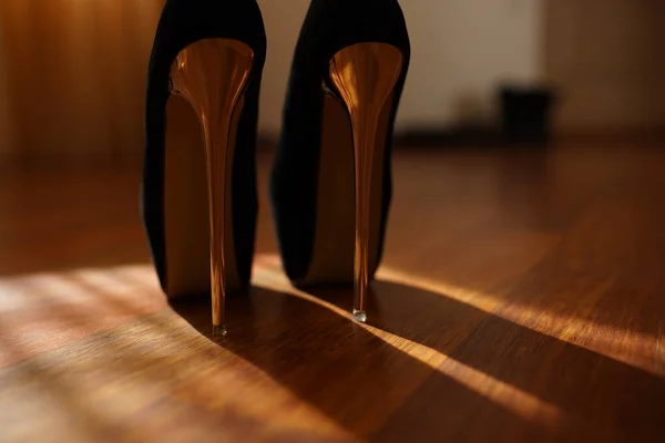 Модные черные женские туфли, золотой блеск на высоком каблуке в темной солнечной комнате . — стоковое фото