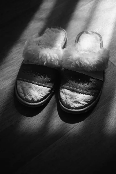 Pantofole da donna con una pelle di pecora su un pavimento di legno. BW — Foto Stock