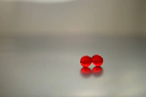 Two red vitamins on a chrome table. Copy space — Stock Photo, Image