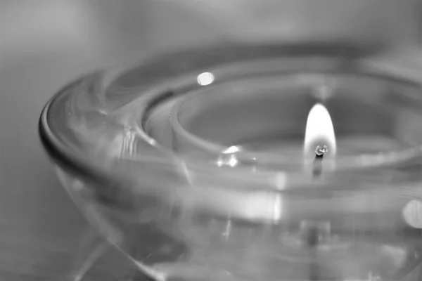 Low candle burns in a round glass candlestick, macro, bw — Stock Photo, Image