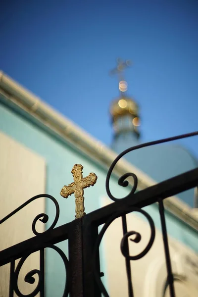 Кованый черный забор с золотым крестом на фоне — стоковое фото