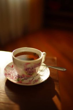 Güneşli masada zarif bir fincanda siyah çay.
