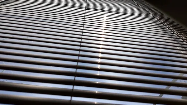 Sonnenschein und geschlossene Jalousien. Jalousie verschwimmt den Hintergrund. Sonnenlicht mit Strahlstraße. — Stockfoto