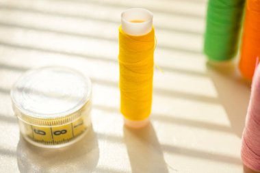 Güneşli bir masada iplik ve terzi makaraları