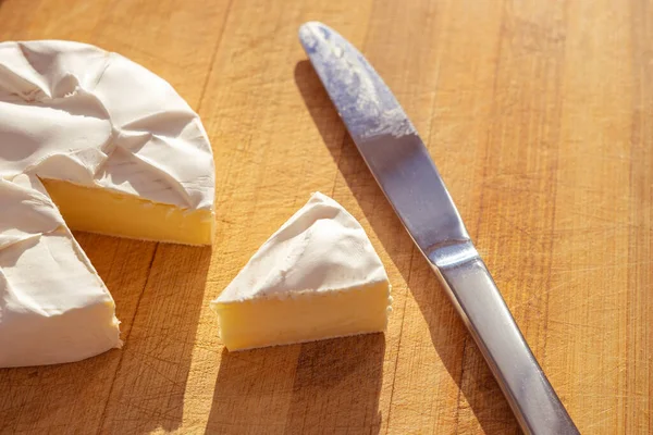 Rebanada Queso Camembert Entero Con Cuchillo Una Tabla Madera Soleada —  Fotos de Stock