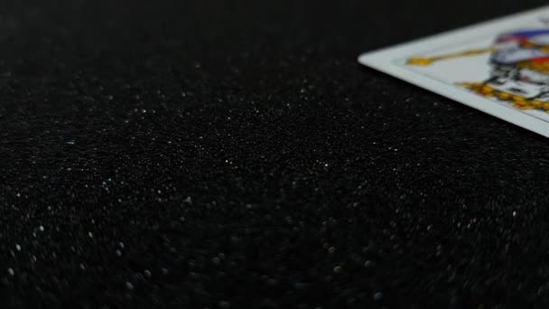 Kralın kartlarının siyah, parlak bir masaya teker teker düşüşünün makro görüntüsü. — Stok video