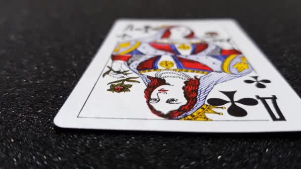Vista lateral de cerca de las cartas de las reinas que caen sobre una mesa negra brillante una a la vez . — Vídeos de Stock