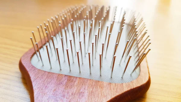 Dřevěný masážní kartáč na vlasy s železnými štětinami na dřevěném stole, detailní záběr, boční pohled. — Stock fotografie