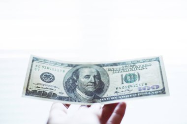 Beyaz bir arka planda 100 dolarlık banknotla el..