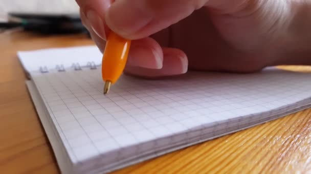 main avec stylo sur une feuille vierge de carnet, pensées hésitantes à écrire ou non.