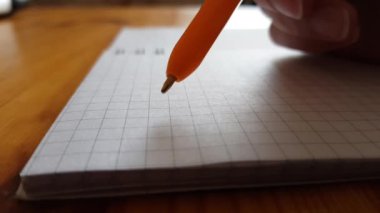 Boş bir defter üzerinde kalem ile el, yazmak ya da yazmamak için tereddütlü düşünceler.
