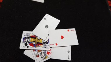 İskambil kağıtları siyah, parlak bir masaya teker teker düşer, yakın plan, yan görüş