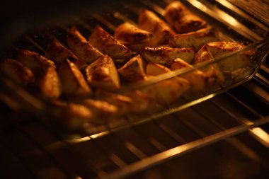 Koyu fırında cam tabakta patates dilimleri..