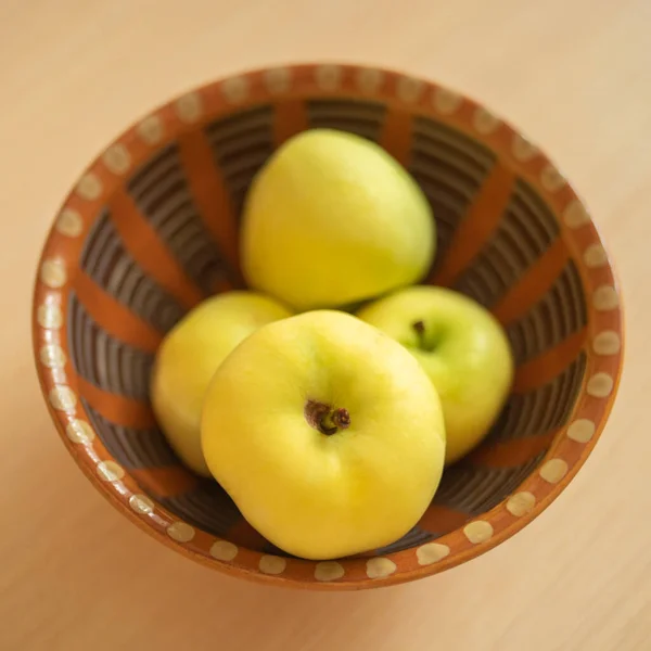 Ripe green apples in a brown clay bowl