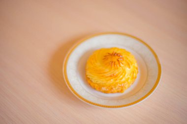 Tahta bir masanın üstünde, beyaz bir tabakta kaymaklı kek.