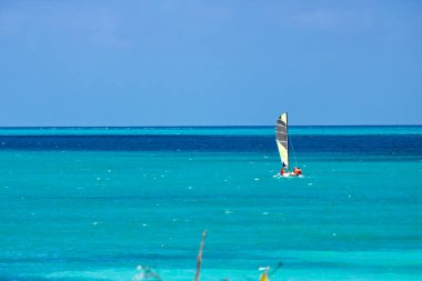 Mavi gökyüzü, Karayip suyunun mavi ve turkuazına karşı ve yelken açan bir katamaran