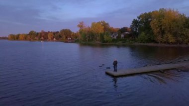 İskelenin sonunda duran bir adamın etrafında dönen hava manzarası.