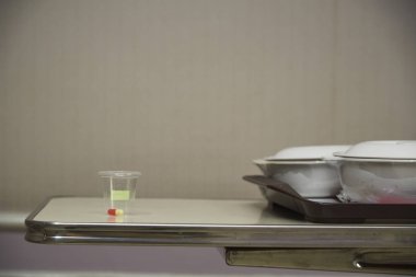 Bir kapsül ilaç yan yemekler ile bir tepsi üzerinde plastik kap içinde.