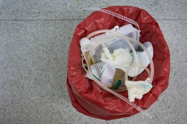 Ameliyathane üzerinde üstten görünüm kırmızı depo gözündeki cerrahi çöp. İdrar torbası ve kateter depo gözünde                               