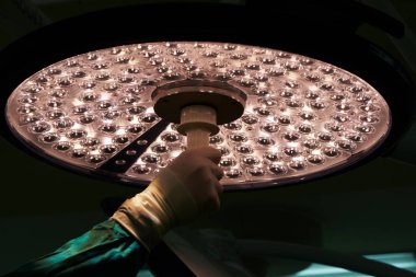 Doktor elini tutarak ve ameliyathane cerrahi lamba ayarlama