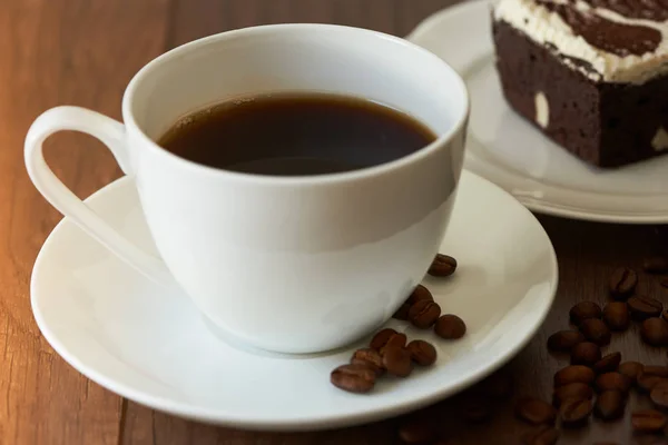 Una sabrosa taza de café caliente y un pedazo de pastel de chocolate en woode — Foto de Stock
