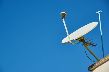 Mavi gökyüzü arka plan karşı çatıda eski bir uydu çanağı