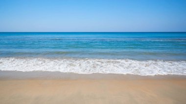 Arka plan açık mavi gökyüzü ve deniz. Sahilde dalgalar deniz