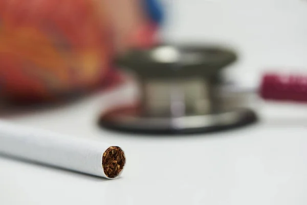 Imagen de primer plano del cigarrillo y el estetoscopio sobre fondo blanco . — Foto de Stock